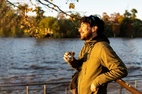 Latin man enjoying the sunset at the river while drinking mate