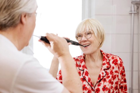 Elderly couple brush their teeth together in the bathroom