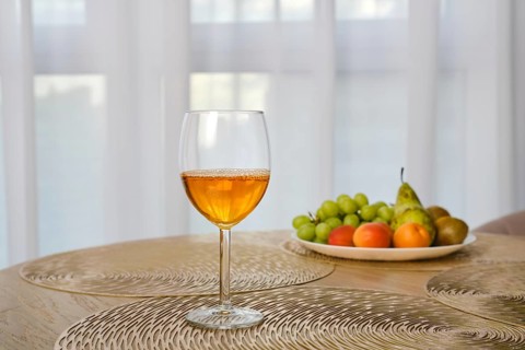 Apple juice in a wine glass on a table with fresh fruits on background