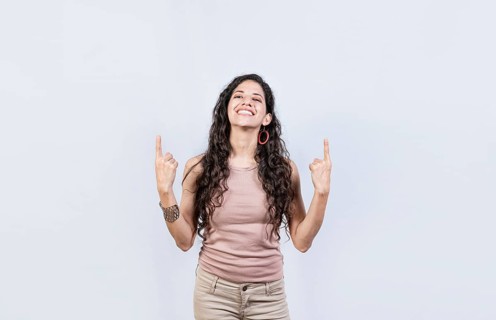 Young girl pointing an advertisement with fingers up. Smiling woman pointing with both fingers up isolated. People recommending with fingers up