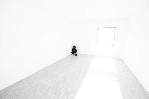 Depressed Woman Sitting on the Floor in a Corner in a Empty Room at Home in Switzerland