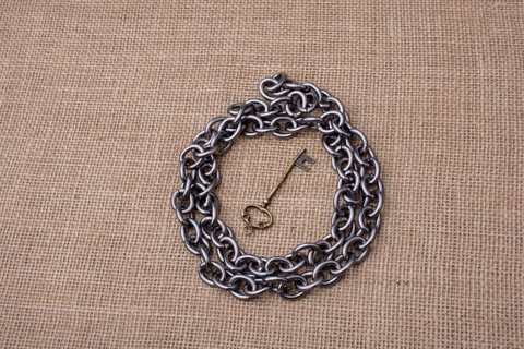 Metal chain around retro styled golden color key