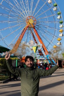 Portrait of latino man in an amusement park posing happy with the ferris wheel in the background