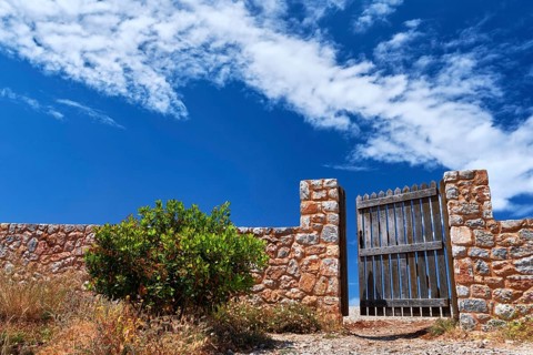 Countryside landscape. Rustic stone wall fence and aged black timber wicket door. Great blue sky with awesome clouds. Concept of opening opportunities