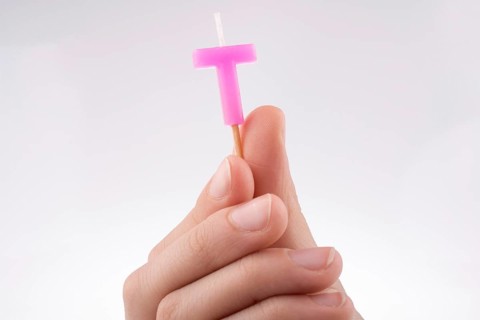 Color candle in hand on sticks writes the letter T