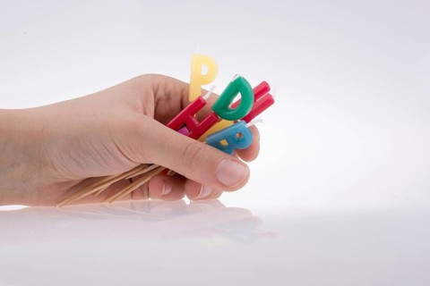 Hand holding letters made of candles on sticks
