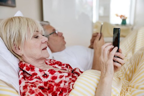 Elderly couple lying in bed together in their bedroom