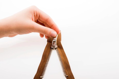 Hand holding color zipper on a white background