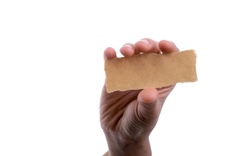Hand holding a piece of blank torn notepaper