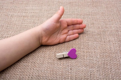 Clothespin with a heart shaped object in hand on canvas
