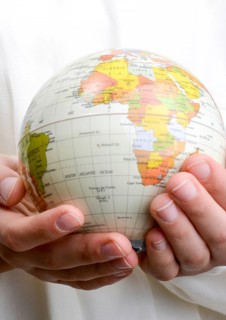 Child holding a small model globe in hand on white background