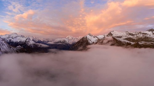 Aerial view over the sea of fog in front of sunrise over the Maloja Pass in autumn