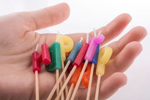 Hand holding letters made of candles on sticks