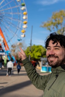 Portrait of latino man in an amusement park posing happy with the ferris wheel in the background