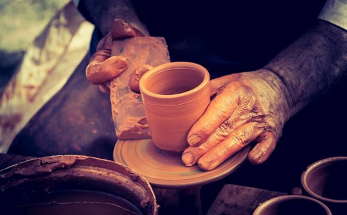 Potter`s hands shaping up the clay of the pot