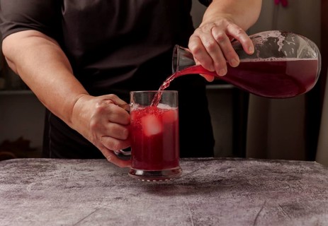 Waitress dressed in black serving a pitcher of sparkling summer red wine on ice from a glass decanter
