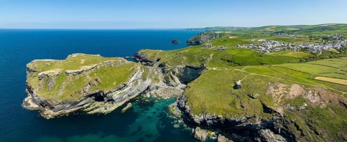 Aerial panorama of the rugged coastline on the Celtic Sea with the Tintagel Peninsula and the ruins of Tintagel Castle