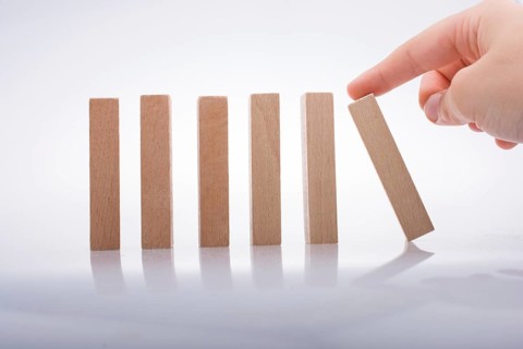 Hand holding wooden domino on a white background