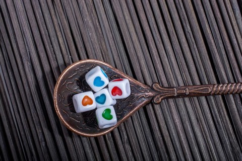 Colorful love cubes in a spoon on a straw mat