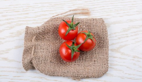 Little canvas sack and red ripe tasty fresh cherry tomatos
