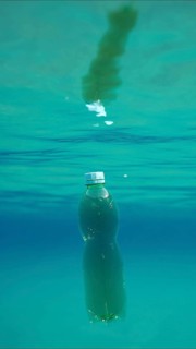 Green plastic bottle drifting under surface of blue water. Plastic pollution of Ocean