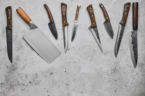 Various types of knives scattered on concrete background