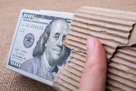 Hand holding banknote bundle of US dollar on a linen canvas background