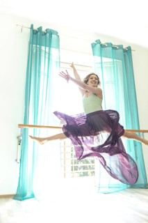 Woman Jumping and Doing the Splits Against a Window with Curtain with Transparent Skirt