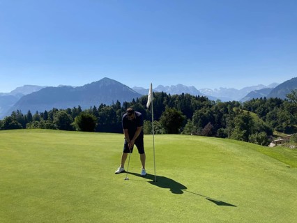Golfer on Putting Green with Mountain View in a Sunny Summer Day in Burgenstock