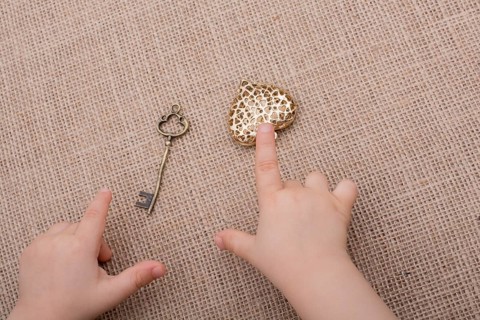 Heart shaped gold color metal object in hand