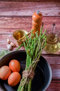 Bunch of wild asparagus in a frying pan with eggs