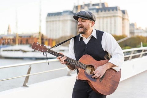 A street musician performing classic songs on guitar