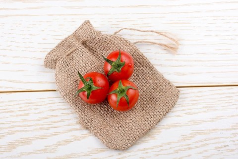 Little canvas sack and red ripe tasty fresh cherry tomatos