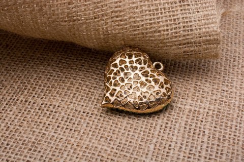 Heart shaped gold color metal object on canvas
