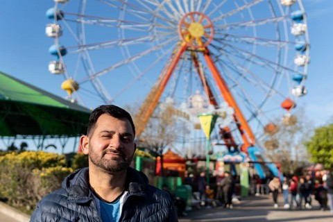 Portrait of latino man in an amusement park posing happy with the ferris wheel in the background