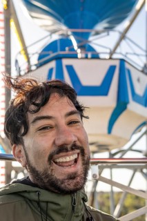 Very excited emotional portrait of a young latin man in the cabin of a ferris wheel. Amusement park adventures and fear of heights