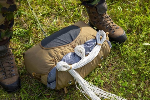 Military Parachuter Standing on the Grass with His Parachute in Switzerland