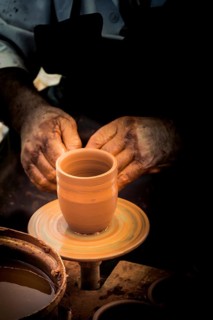 Potter`s hands shaping up the clay of the pot