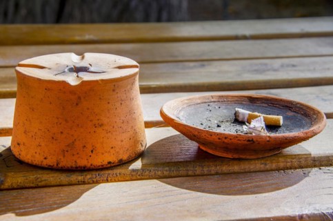 Stylish ashtray with cigarette butt on a wooden table