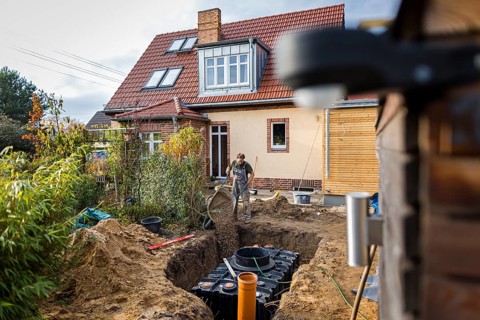 A man installs a water cistern in the garden next to his house to be able to water his garden with rainwater. Berlin