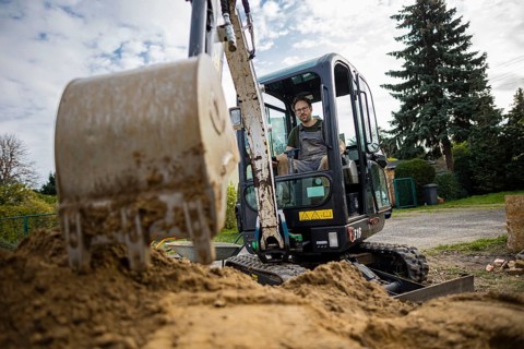 A construction worker sits in a mini-excavator at a building site. Berlin