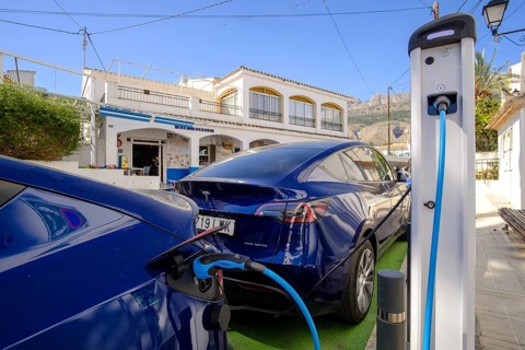 Two Tesla electric vehicles charging at a charging station in the village of Altea La Vella