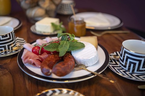 Set dining table with golden cutlery and a cheese and sausage platter