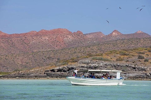 Tourist boat sailing along the rocky coastline of Isla Espiritu Santo