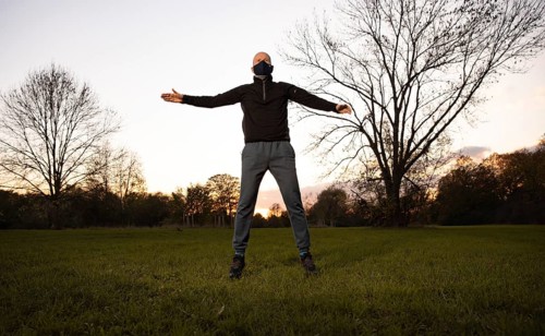 Man with mask stretches in a meadow in autumn.