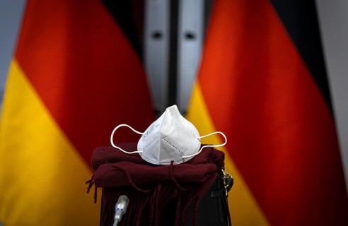 An FFP2 mask lies in front of Germany flags at the Federal Foreign Office. Berlin. 09.12.2020