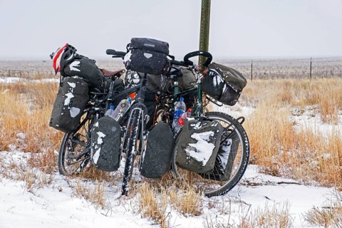 Two heavily laden trekking bicycles with big panniers in the snow in winter