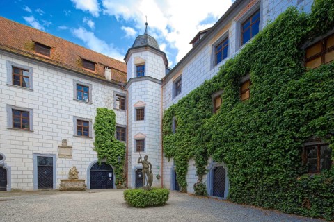 Inner courtyard of Mitwitz moated castle with Neptune fountain and sandstone statue of The Franconian Knight