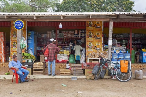 Touring cyclist buying food at roadside grocery shop