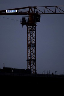 A worker draws on scaffolding and in front of a crane on a newly built house